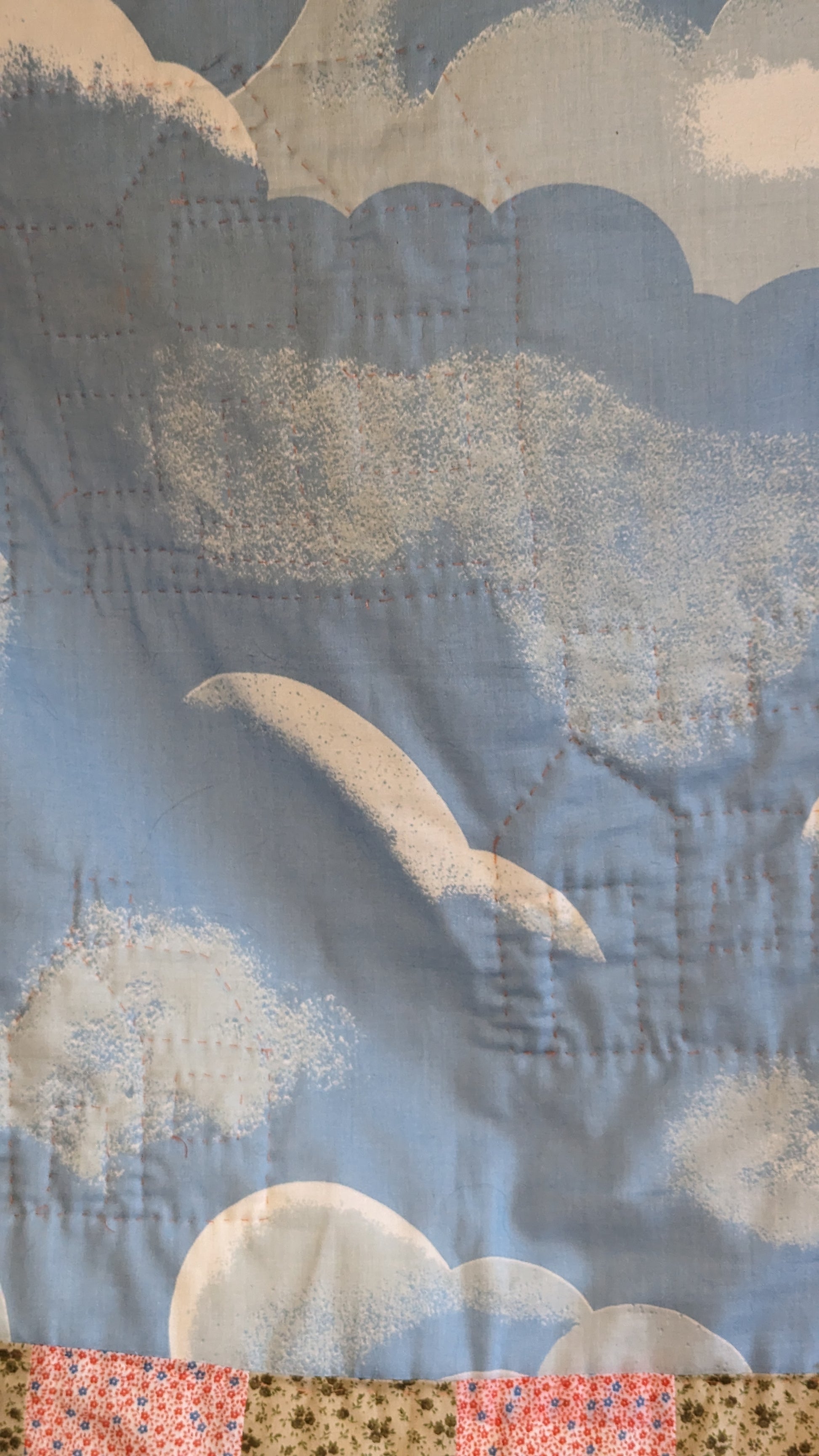 close up hand stitched house shaped quilting on blue cloudy sky