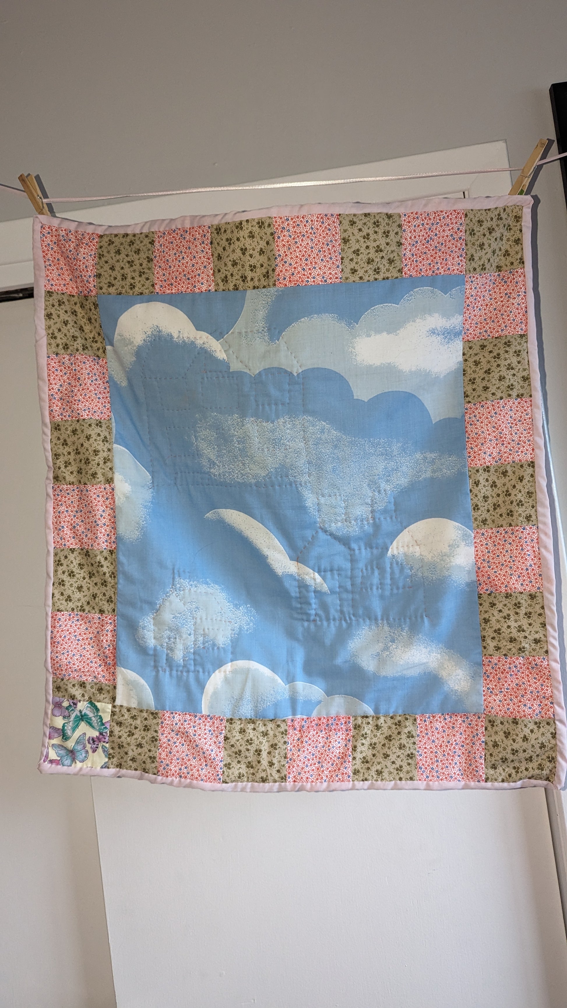 small quilt hanging on a clothesline with colthespins